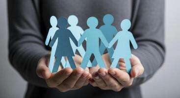 Hands holding light blue paper cut out figures symbolizing community and support photo