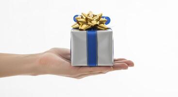 Woman hand holding a silver gift box with blue ribbon and gold bow for celebration photo