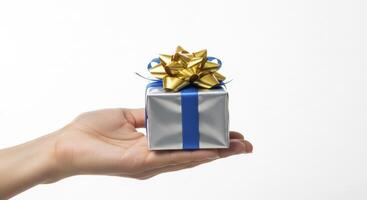 Woman hand holding a silver gift box with blue ribbon and gold bow for celebration. photo