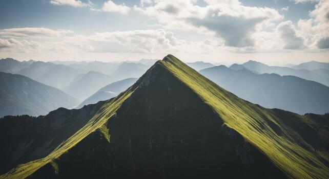 Sharply pointed green mountain peak under a bright sky with distant ranges photo