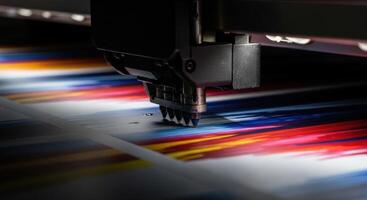 Close up of a large format industrial printer print head applying vibrant colorful ink onto paper. photo