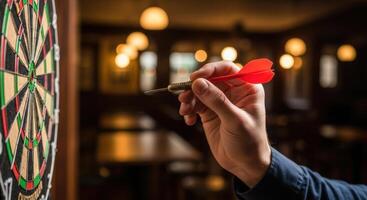 Close up of a hand holding a red dart aiming at a dartboard, ready to throw in a pub setting photo
