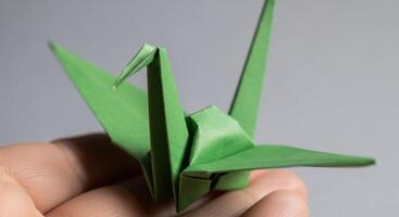 Green Origami Crane Held Gently in a Hand Showcasing Japanese Paper Art and Craft photo