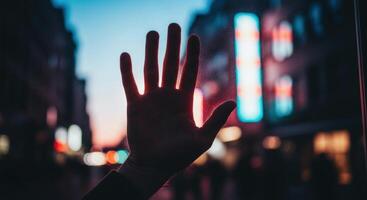 Human Hand Silhouette Against Blurry City Lights at Dusk Creating an Invisible Barrier photo