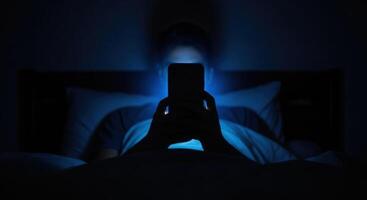 Blue light from smartphone screen illuminates face of individual in dark bed at night photo