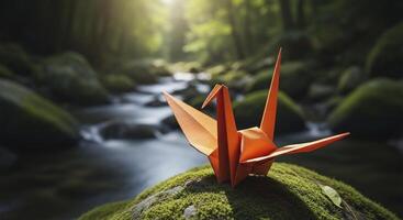 Vibrant Orange Origami Crane Perched on Mossy Rock by Stream in Sunlit Forest photo