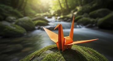 Vibrant Orange Origami Crane Perched on Mossy Rock by a Flowing Forest Stream photo