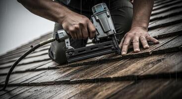 Roofer Using Nail Gun to Install Shingles on a Wet Roof During Rain photo