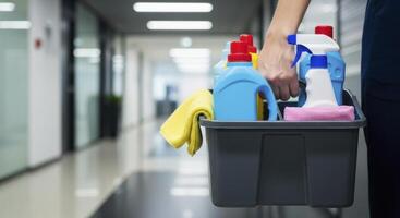 Professional Cleaner Carrying Caddy with Supplies in Modern Office Hallway photo