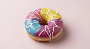 Brightly Colored Donut with Vibrant Icing and White Drizzle on a Pink Surface photo