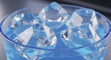 Clear geometric ice cubes floating in a vibrant blue drink inside a glass photo