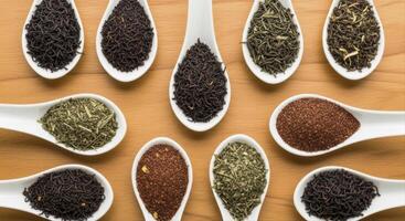Assortment of dry loose leaf tea varieties in white spoons on a wooden surface photo
