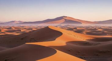 Panoramic view of vast reddish orange sand dunes under a clear sky at sunrise photo