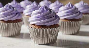 Row of freshly baked cupcakes with vibrant purple frosting and silver wrappers photo