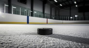 Black Hockey Puck Resting on Textured Ice Surface in an Empty Ice Hockey Arena photo