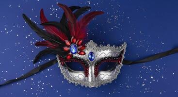 Elegant Silver Masquerade Mask with Red Feathers and Jewels on Blue Background photo