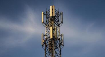 Tall cellular communication tower with multiple antennas against a clear blue sky photo