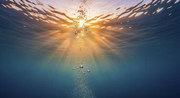 Underwater view with sun rays piercing through the clear blue water and rising air bubbles photo