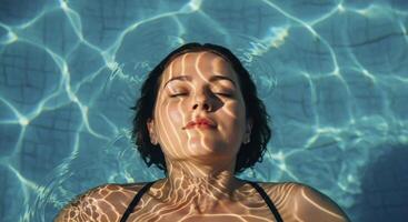 Woman Floating in Swimming Pool with Sunlight Reflections on Her Face photo