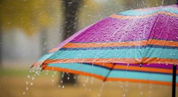 Colorful striped umbrella covered in glistening raindrops during a peaceful autumn shower. photo