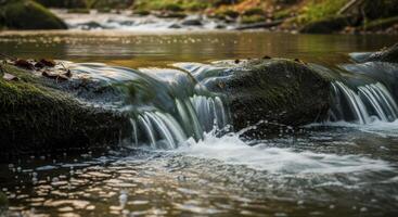 Gentle cascade of water flowing over mossy rocks in a serene forest stream photo