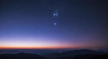 Starry night sky with constellations over mountain silhouettes at twilight photo