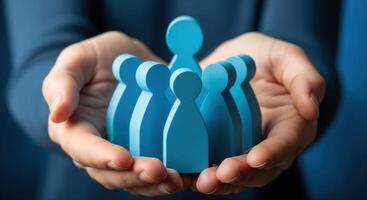 Hands gently holding a group of blue stylized figures representing community and teamwork photo