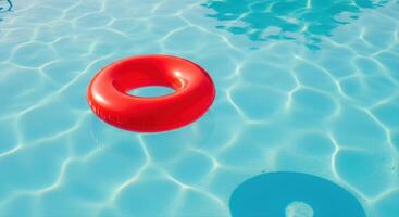 Bright red inflatable ring float gently drifting on clear blue swimming pool water photo