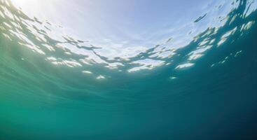 Underwater view of ocean surface with bright sunlight and clear blue water photo