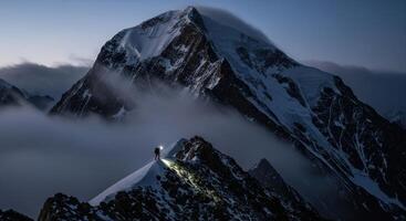 Lone climber with headlamp on a snowy mountain ridge at dawn amidst clouds photo