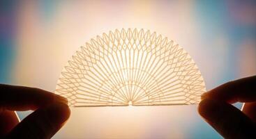 Delicate translucent fan shaped wafer with intricate patterns held by human hand photo