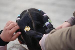 Young child has hair braided with colorful rubber bands in a playful setting photo