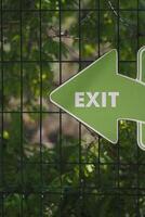 Green exit sign pointing left in nature setting photo
