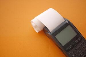 Old thermal printer on orange background with paper roll photo