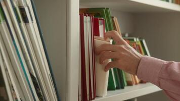 Nahansicht von männlich Schüler Hand pflücken Buch von Regal im Bibliothek unkenntlich Mann Kerl wählen Literatur akademisch Forschung Wissen Suche Bildung Prozess studieren im Universität Schule Lernen video