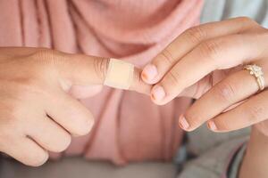 Hands applying a bandage on a finger at home photo