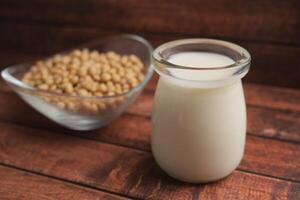 Creamy soy milk with soybeans on wooden table photo
