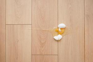 Eggshells and yolk spill on wooden floor photo