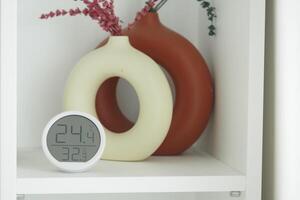 Decorative vases and digital temperature display on shelf photo