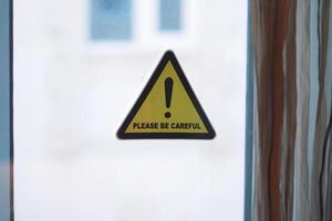 Warning sign urging caution near a window photo