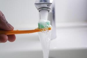 Brushing teeth at a bathroom sink with flowing water photo