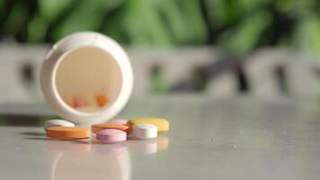 Colorful tablets spill from a container on a table video