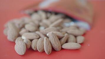 Almonds are spilled from a bag onto a bright surface, video