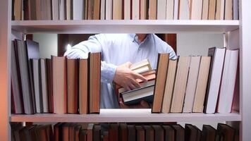 A man is holding a book in front of a book shelf video