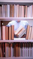 uma homem é olhando às uma livro estante com muitos livros video