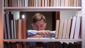 A man is leaning on a bookshelf with his head in the middle video