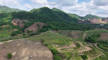 A peaceful aerial view of a winding dirt road cutting through green hills, with dense clouds gathering overhead. The calm atmosphere captures the moment before a rainstorm in the countryside. video