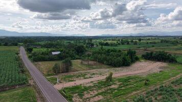 Aerial drone footage showing a winding road weaving through rolling green hills under a cloudy sky, moments before a summer rainstorm. Peaceful and cinematic rural scenery. video