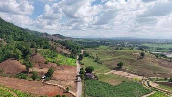 A peaceful aerial view of a paved road winding through lush green hills, with a dramatic cloudy sky hinting at an approaching rainstorm. video
