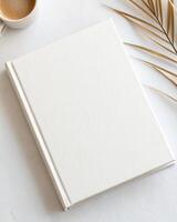 White blank notebook with palm leaves on white marble photo
